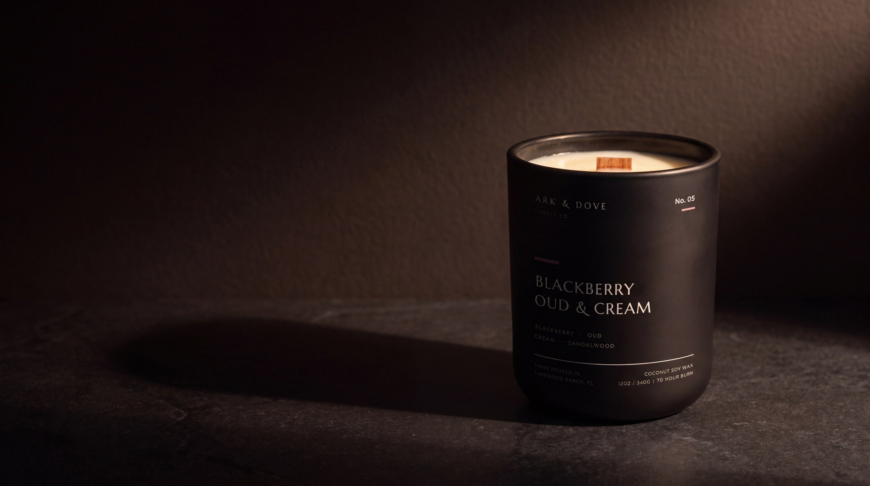 A matte black Ark & Dove candle, No. 05 Blackberry Oud & Cream, on dark stone
